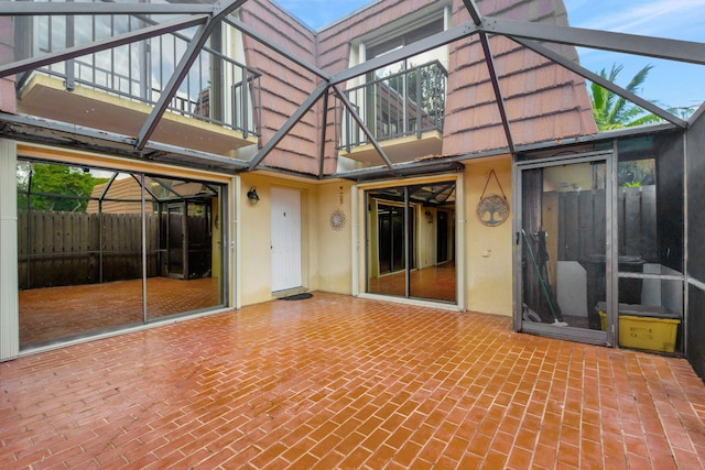 back of property with glass enclosure and a balcony