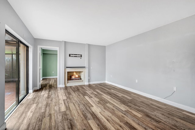 1707 17th Ln, Palm Beach Gardens, FL 33418 - unfurnished living room with wood finished floors, a lit fireplace, and baseboards