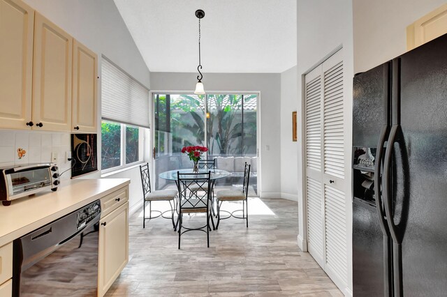 kitchen with pendant lighting, lofted ceiling, black appliances, light hardwood / wood-style flooring, and tasteful backsplash