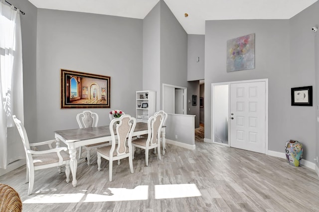 dining space featuring light hardwood / wood-style floors and high vaulted ceiling