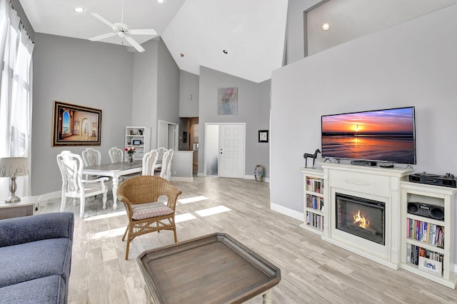 living room with ceiling fan, high vaulted ceiling, and light wood-type flooring