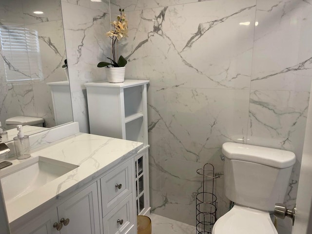 bathroom with vanity, tile walls, and toilet