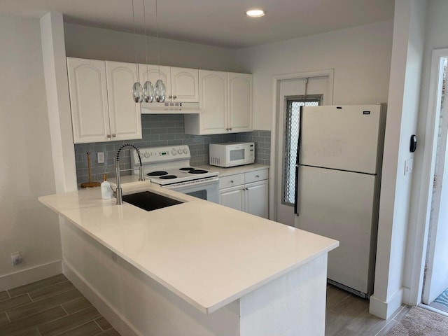 kitchen with white appliances, sink, kitchen peninsula, dark hardwood / wood-style floors, and white cabinetry