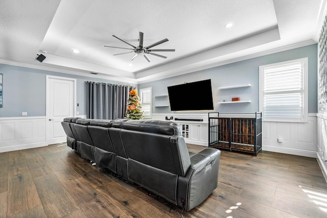 living room with dark hardwood / wood-style flooring, a raised ceiling, and crown molding