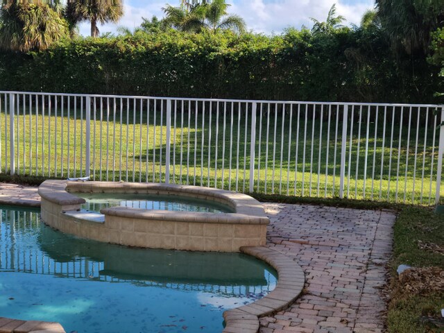 view of swimming pool featuring an in ground hot tub and a yard