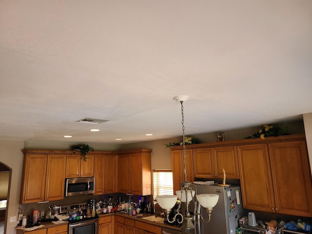 kitchen featuring pendant lighting, appliances with stainless steel finishes, and tasteful backsplash