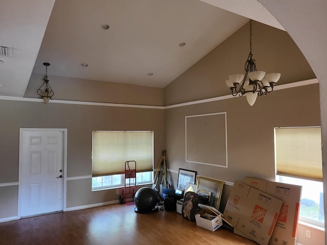 misc room featuring hardwood / wood-style floors, high vaulted ceiling, ornamental molding, and an inviting chandelier