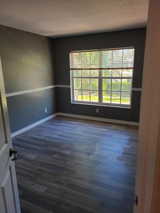 spare room featuring dark hardwood / wood-style floors and a textured ceiling