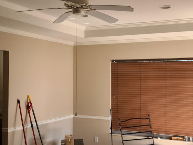 interior space with a tray ceiling, ceiling fan, and crown molding