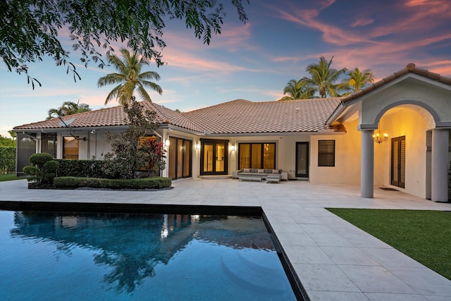 back house at dusk featuring an outdoor living space and a patio area