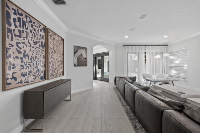 living room with a textured ceiling, light wood-type flooring, and crown molding