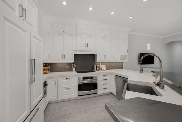 kitchen with kitchen peninsula, appliances with stainless steel finishes, crown molding, sink, and white cabinetry