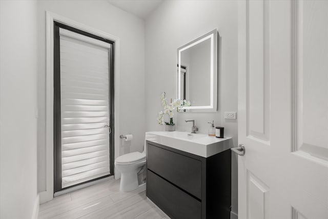 bathroom with hardwood / wood-style floors, vanity, and toilet