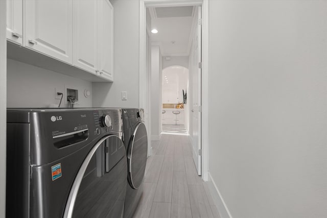 laundry area featuring independent washer and dryer, cabinets, and light wood-type flooring