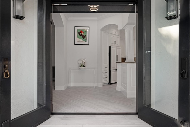 hallway with light wood-type flooring and ornamental molding