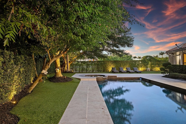 pool at dusk featuring an in ground hot tub