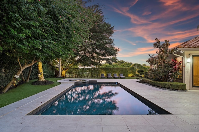 pool at dusk with an in ground hot tub and a patio