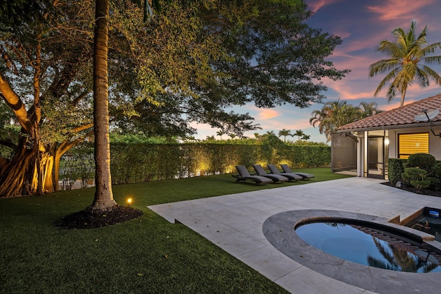 pool at dusk featuring an in ground hot tub, a yard, and a patio