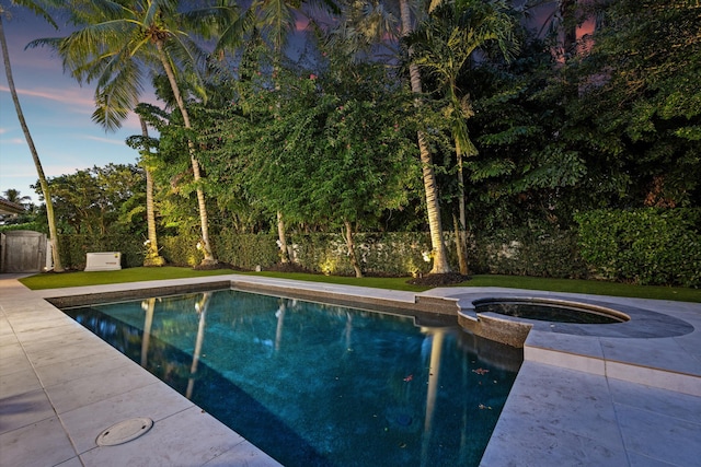 pool at dusk with an in ground hot tub