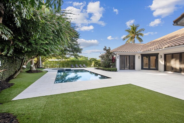 view of swimming pool featuring a patio area, a yard, and an in ground hot tub