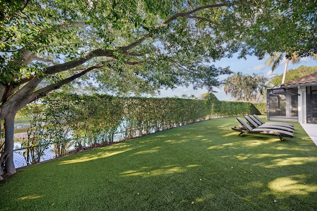 view of yard with a sunroom and a water view