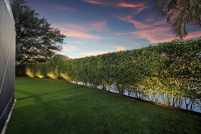 yard at dusk featuring a water view