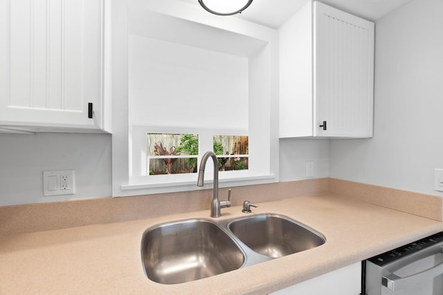 kitchen with dishwasher, white cabinetry, and sink