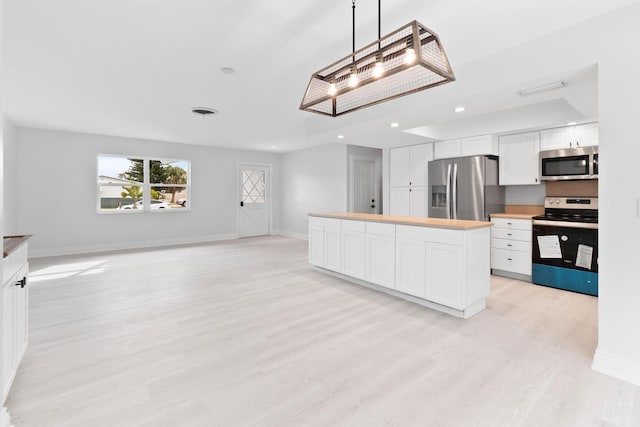 kitchen featuring a center island, light hardwood / wood-style floors, decorative light fixtures, white cabinets, and appliances with stainless steel finishes