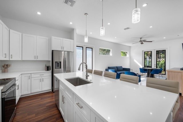 kitchen featuring white cabinetry, sink, decorative light fixtures, and stainless steel appliances