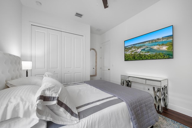 bedroom with dark wood-type flooring, ceiling fan, and a closet