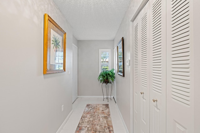 hall featuring light tile patterned flooring and a textured ceiling