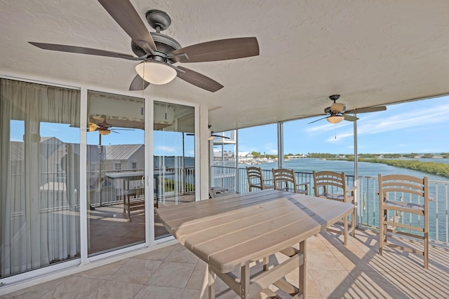 sunroom / solarium featuring a water view and ceiling fan