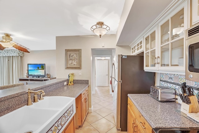 kitchen featuring ceiling fan, sink, appliances with stainless steel finishes, and light tile patterned flooring