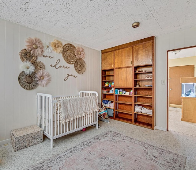 carpeted bedroom featuring wood walls and a crib