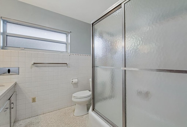 full bathroom with shower / bath combination with glass door, vanity, toilet, and tile walls