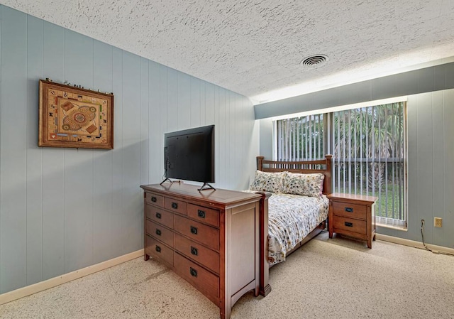 bedroom featuring wooden walls and a textured ceiling