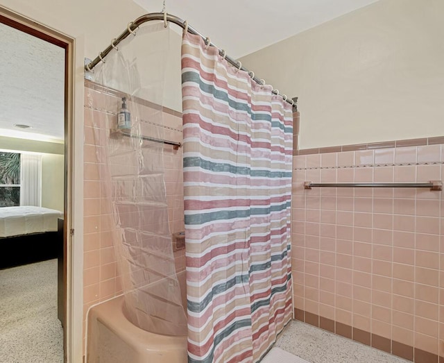 bathroom featuring shower / bath combination with curtain and tile walls