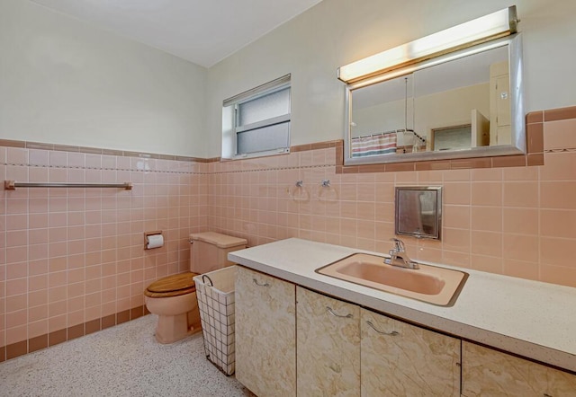 bathroom with vanity, toilet, and tile walls