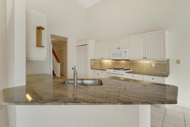 kitchen with sink, white cabinets, light tile patterned floors, kitchen peninsula, and white appliances