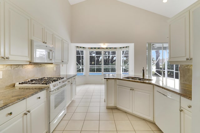 kitchen featuring sink, high vaulted ceiling, light tile patterned floors, white appliances, and white cabinets