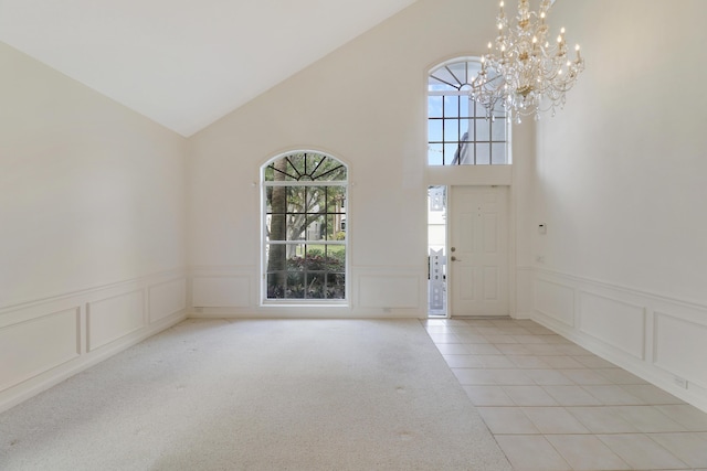 foyer featuring vaulted ceiling, light colored carpet, and a chandelier