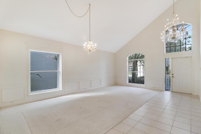 interior space with light carpet, a notable chandelier, and high vaulted ceiling