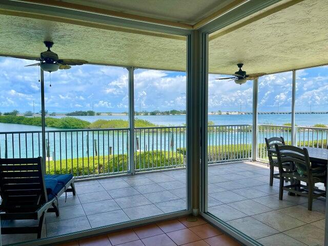 sunroom featuring ceiling fan and a water view