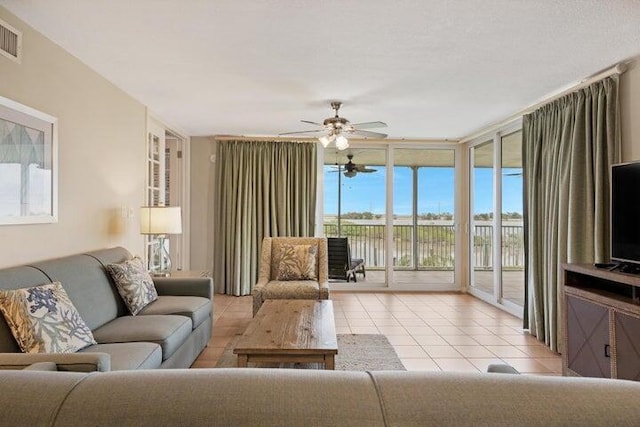 tiled living room with ceiling fan and floor to ceiling windows