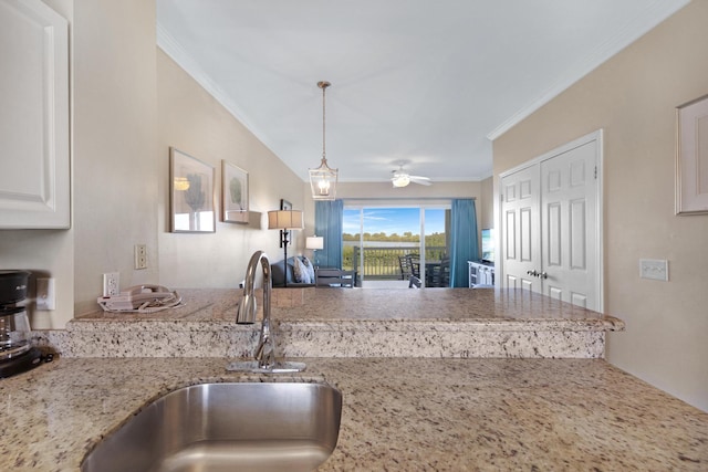 kitchen featuring hanging light fixtures, light stone countertops, ceiling fan, ornamental molding, and sink