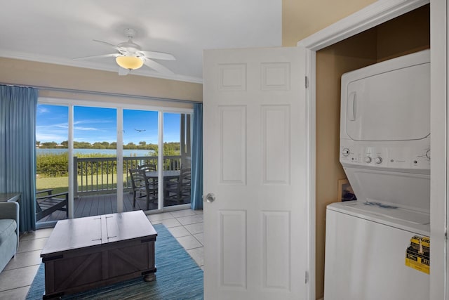 laundry area with stacked washing maching and dryer, ceiling fan, light tile patterned floors, and crown molding