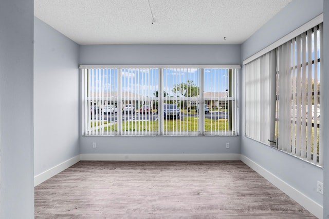 unfurnished room with light hardwood / wood-style floors and a textured ceiling