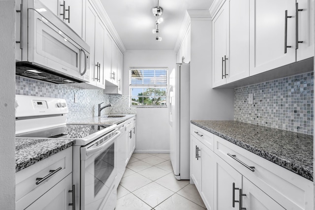 kitchen featuring decorative backsplash, white cabinetry, dark stone countertops, and white appliances