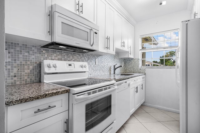 kitchen with light tile patterned floors, white appliances, white cabinetry, and backsplash