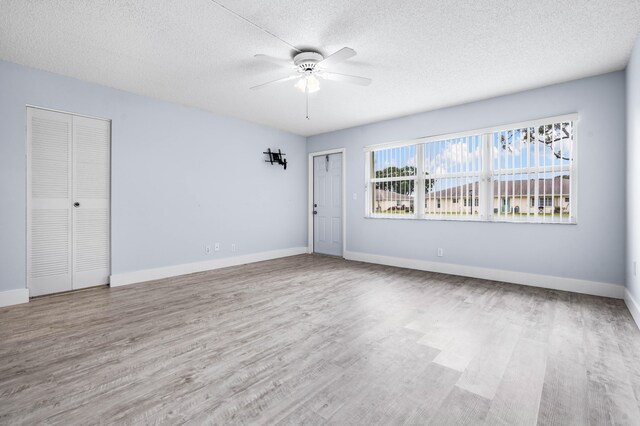 unfurnished room with ceiling fan, light hardwood / wood-style flooring, and a textured ceiling